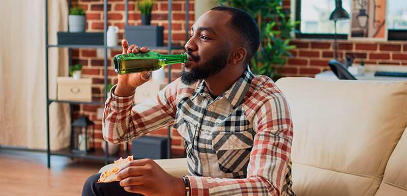 Imagem de um homem ingerindo bebida alcoólica, que é uma das causas do mau hálito. 