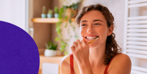 Mulher jovem escovando os dentes e sorrindo